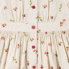Close detail of embroidered cherry print and smocking on a Happyology cotton dress